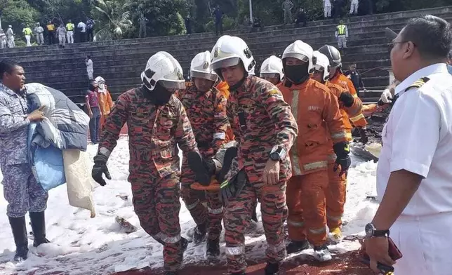 CORRECTS THE SOURCE - In this photo released by Fire &amp; Rescue Department of Malaysia, fire and rescue department move out a body from the crash site of two helicopter in Lumur, Perak state, Monday, April 23, 2024. Malaysia's navy says two military helicopters collided and crashed during a training session, killing all 10 people on board. (Fire &amp; Rescue Department of Malaysia via AP)