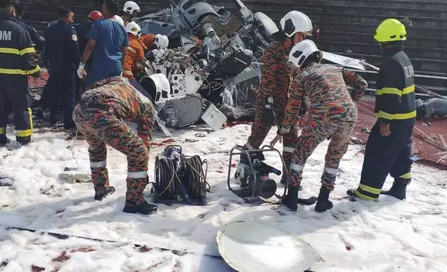 CORRECTS THE SOURCE - In this photo released by Fire &amp; Rescue Department of Malaysia, fire and rescue department inspect the crash site of two helicopter in Lumur, Perak state, Monday, April 23, 2024. Malaysia's navy says two military helicopters collided and crashed during a training session, killing all 10 people on board. (Fire &amp; Rescue Department of Malaysia via AP)