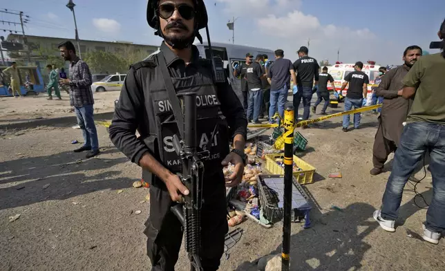 CORRECTS DATE - A police officer stands guard at the site of a suicide attack in Karachi, Pakistan, Friday, April 19, 2024. Five Japanese nationals traveling in a van narrowly escaped a suicide attack when a suicide bomber detonated his explosive-laden vest near their vehicle in Pakistan's port city of Karachi on Friday, wounding three passers-by, police said. (AP Photo/Fareed Khan)