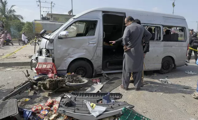CORRECTS DATE - Pakistani investigators examine a damaged van at the site of a suicide attack in Karachi, Pakistan, Friday, April 19, 2024. Five Japanese nationals traveling in a van narrowly escaped a suicide attack when a suicide bomber detonated his explosive-laden vest near their vehicle in Pakistan's port city of Karachi on Friday, wounding three passers-by, police said. (AP Photo/Fareed Khan)