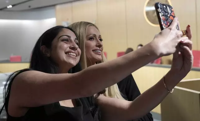 Aparra Agnihotri, left, takes a selfie with hotel heiress and media personalty Paris Hilton in Sacramento, Calif., Monday, April 15, 2024. Hilton, who has shared publicly the physical and mental abuse she suffered as a teenager at a boarding school in Utah, urged members of the Senate Human Services Committee to approve proposed bill by state Sen. Shannon Grove, R-Bakersfield, for more transparency for youth treatment facilities licensed by the California Department of Social Services. (AP Photo/Rich Pedroncelli)