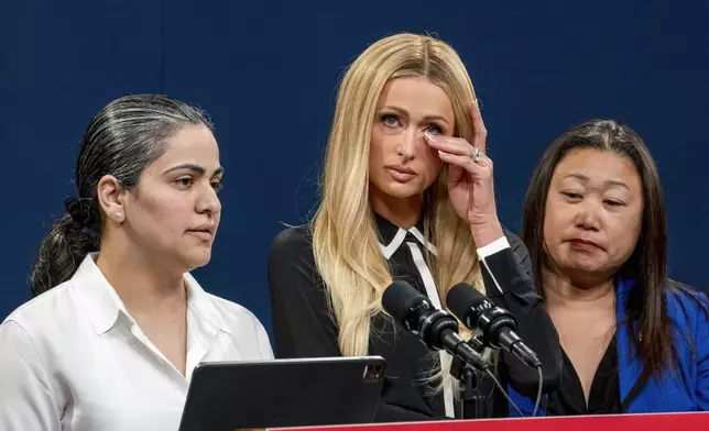 Hotel heiress and media personalty Paris Hilton, center, wipes her eyes as state Sen. Aisha Wahab, D-Fremont, left, talks in support of a proposed bill calling on more transparency for youth treatment facilities during a news conference in Sacramento, Calif., Monday, April 15, 2024. At right is state Sen. Janet Nguyen, R-Huntington Beach. (AP Photo/Rich Pedroncelli)