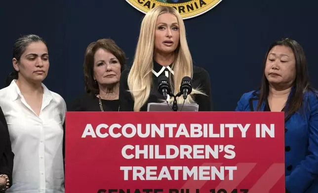 Hotel heiress and media personalty Paris Hilton, center, discusses a proposed bill calling on more transparency for youth treatment facilities during a news conference in Sacramento, Calif., Monday, April 15, 2024. (AP Photo/Rich Pedroncelli)