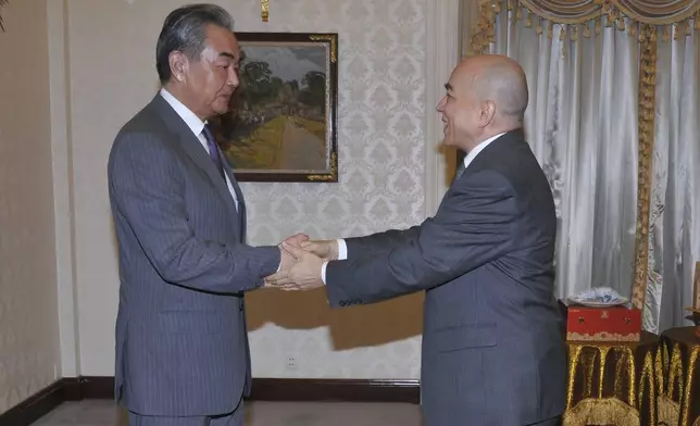 In this photo released by Agence Kampuchea Press (AKP), Chinese Foreign Minister Wang Yi, left, greets with Cambodia's King Norodom Sihamoni, right, in Royal Palace, in Phnom Penh, Cambodia, Sunday, April 21, 2024. Wang Yi, arrived Cambodia to mark his 3 days official visit (21-23 April) Cambodia to reaffirm his country's commitment and to boost the already firmly tied to southeast Asian country, twice visited in the last eight months. (AKP via AP)