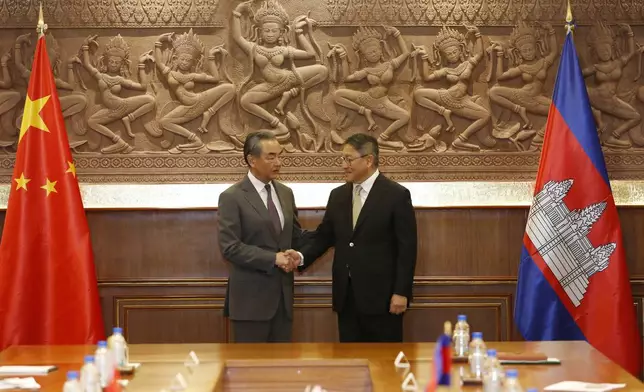 In this photo released by Agence Kampuchea Press (AKP), Chinese Foreign Minister Wang Yi, left, greets with Cambodia's Foreign Minister, SOK Chenda Sophea, right, in Phnom Penh, Cambodia, Sunday, April 21, 2024. Wang Yi, arrived Cambodia to mark his 3 days official visit (21-23 April) Cambodia to reaffirm his country's commitment and to boost the already firmly tied to southeast Asian country, twice visited in the last eight months. (AKP via AP)