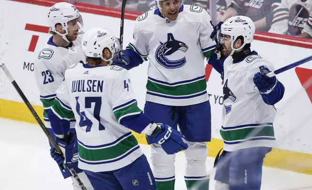 Vancouver Canucks' Elias Lindholm (23), Noah Juulsen (47), Dakota Joshua (81) and Conor Garland (8) celebrate Garland's goal against the Winnipeg Jets during the first period of an NHL hockey game Thursday, April 18, 2024, in Winnipeg, Manitoba. (John Woods/The Canadian Press via AP)