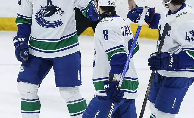 Vancouver Canucks' Elias Lindholm (23), Conor Garland (8) and Quinn Hughes (43) celebrate Lindholm's goal against the Winnipeg Jets during the second period of an NHL hockey game Thursday, April 18, 2024, in Winnipeg, Manitoba. (John Woods/The Canadian Press via AP)