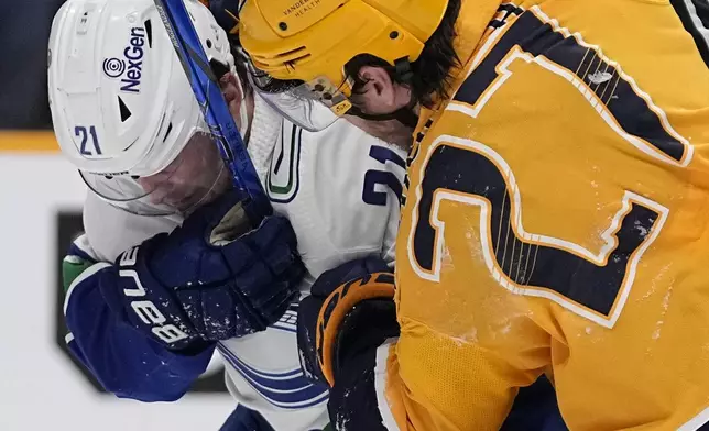 Vancouver Canucks left wing Nils Hoglander (21) and Nashville Predators defenseman Ryan McDonagh (27) fight during the first period in Game 3 of an NHL hockey Stanley Cup first-round playoff series Friday, April 26, 2024, in Nashville, Tenn. (AP Photo/George Walker IV)