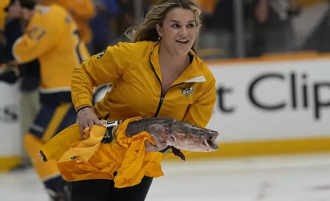 A worker skates a catfish off the ice before Game 3 of an NHL hockey Stanley Cup first-round playoff series between the Nashville Predators and the Vancouver Canucks, Friday, April 26, 2024, in Nashville, Tenn. (AP Photo/George Walker IV)