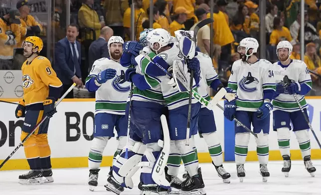 Vancouver Canucks players celebrate the team's 4-3 overtime win against the Nashville Predators in Game 4 of an NHL hockey Stanley Cup first-round playoff series Sunday, April 28, 2024, in Nashville, Tenn. (AP Photo/George Walker IV)