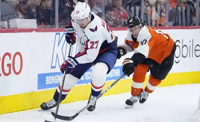 Washington Capitals' Alexander Alexeyev, left, tries to keep the puck away from Philadelphia Flyers' Bobby Brink during the second period of an NHL hockey game, Tuesday, April 16, 2024, in Philadelphia. (AP Photo/Matt Slocum)