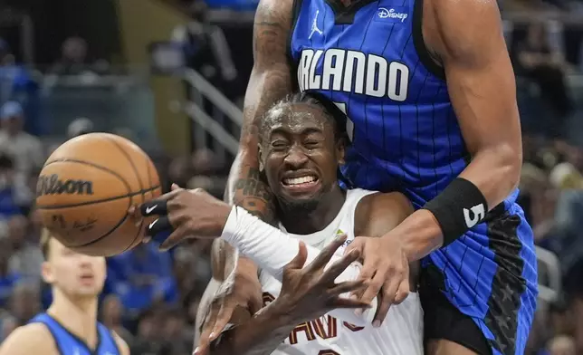 Orlando Magic forward Paolo Banchero, top, fouls Cleveland Cavaliers guard Caris LeVert (3) on a shot attempt during the first half of Game 3 of an NBA basketball first-round playoff series Thursday, April 25, 2024, in Orlando, Fla. (AP Photo/John Raoux)