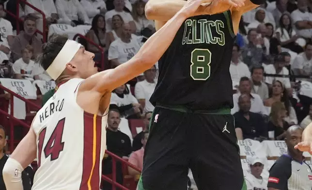 Miami Heat guard Tyler Herro (14) fouls Boston Celtics center Kristaps Porzingis (8) during the first half of Game 4 of an NBA basketball first-round playoff series, Monday, April 29, 2024, in Miami. (AP Photo/Marta Lavandier)