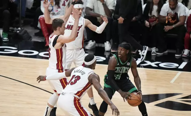 Boston Celtics guard Jrue Holiday (4) looks for an opening past Miami Heat center Bam Adebayo (13) forward Nikola Jovic, far left, and guard Tyler Herro, rear, during the first half of Game 3 of an NBA basketball first-round playoff series, Saturday, April 27, 2024, in Miami. (AP Photo/Wilfredo Lee)