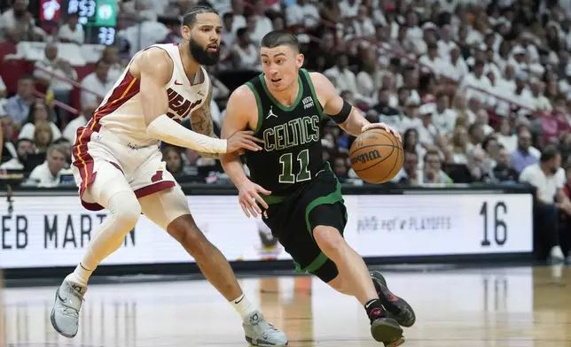 Boston Celtics guard Payton Pritchard (11) drives to the basket past Miami Heat forward Caleb Martin (16) during the first half of Game 3 of an NBA basketball first-round playoff series, Saturday, April 27, 2024, in Miami. (AP Photo/Wilfredo Lee)