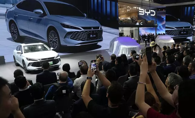 Attendees take photos of the BYD Qin L Dmi unveiled during Auto China 2024 held in Beijing, Thursday, April 25, 2024. (AP Photo/Ng Han Guan)