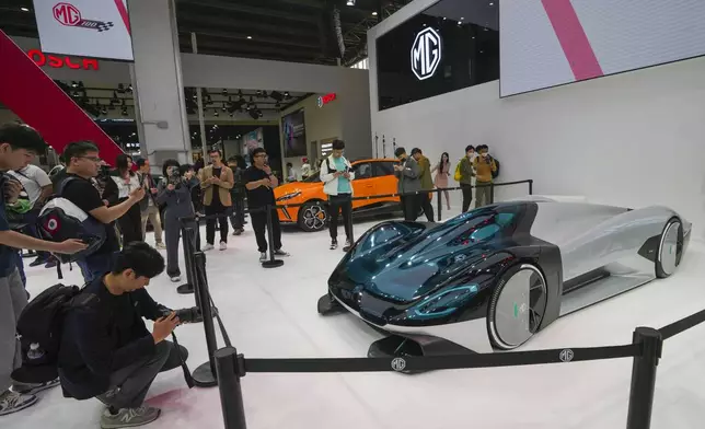 Visitors take photos of a MG concept car during an opening of China Auto Show in Beijing, China, Thursday, April 25, 2024. (AP Photo/Tatan Syuflana)