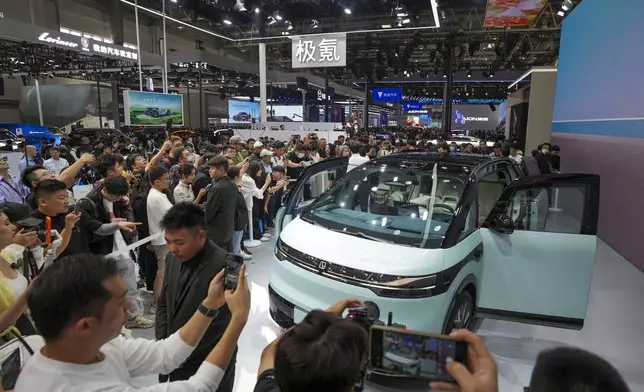 Visitors take photos of a Zeekr car during the opening of China Auto Show in Beijing, China, Thursday, April 25, 2024. (AP Photo/Tatan Syuflana)