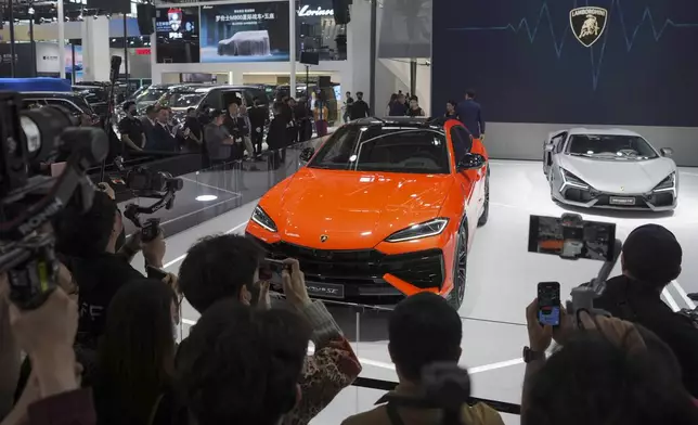 Visitors photograph a Lamborghini car during the opening of China Auto Show in Beijing, China, Thursday, April 25, 2024. (AP Photo/Tatan Syuflana)