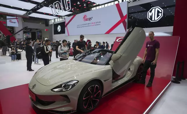 Visitors look at an MG car during the opening of China Auto Show in Beijing, China, Thursday, April 25, 2024. (AP Photo/Tatan Syuflana)