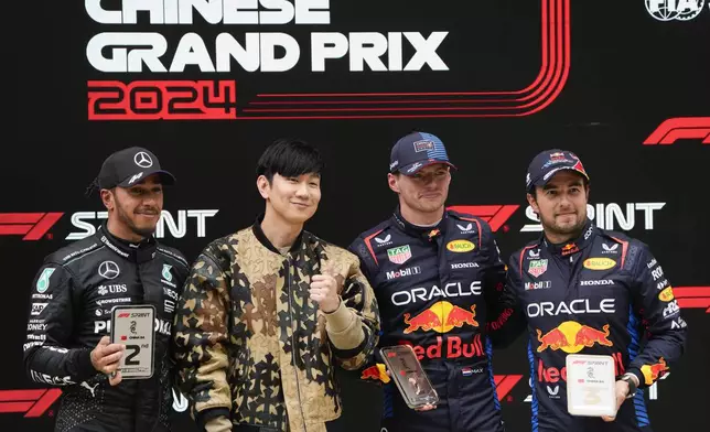 Singapore singer JJ Lin, second left, stands with sprint race winner Red Bull driver Max Verstappen of the Netherlands, second placed Mercedes driver Lewis Hamilton, left, of Britain and third placed Red Bull driver Sergio Perez, right, of Mexico at the Chinese Formula One Grand Prix at the Shanghai International Circuit, Shanghai, China, Saturday, April 20, 2024. (AP Photo/Andy Wong)