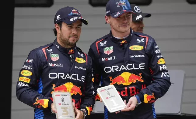 Sprint race winner Red Bull driver Max Verstappen, right, of the Netherlands stands with teammate and third placed Sergio Perez of Mexico at the Chinese Formula One Grand Prix at the Shanghai International Circuit, Shanghai, China, Saturday, April 20, 2024. (AP Photo/Andy Wong)