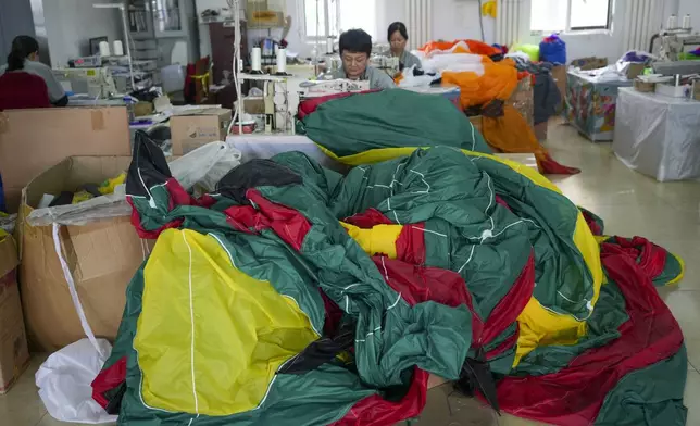 Workers stitch kites at a workshop in Weifang, Shandong Province of China, Friday, April 19, 2024. (AP Photo/Tatan Syuflana)