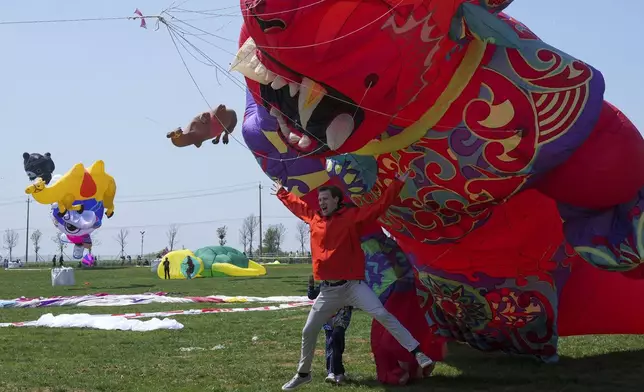 A visitor poses in front of a giant kite at the 41st International Kite Festival in Weifang, Shandong Province of China, Saturday, April 20, 2024. (AP Photo/Tatan Syuflana)