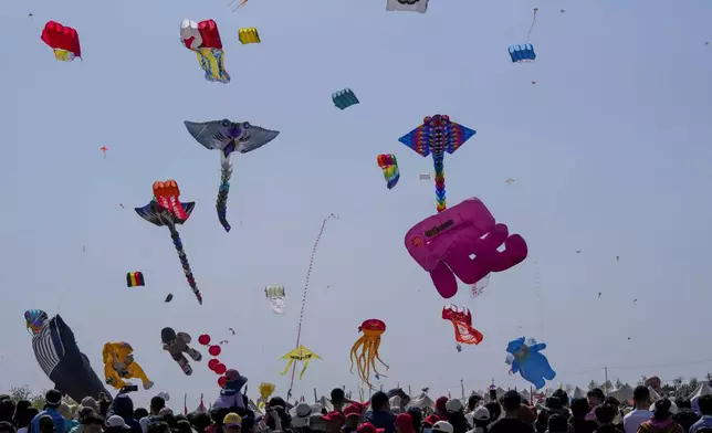 Visitors watch kites fly at the 41st International Kite Festival in Weifang, Shandong Province of China, Saturday, April 20, 2024. (AP Photo/Tatan Syuflana)