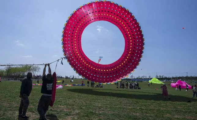 Participants fly a kite at the 41st International Kite Festival in Weifang, Shandong Province of China, Saturday, April 20, 2024. (AP Photo/Tatan Syuflana)