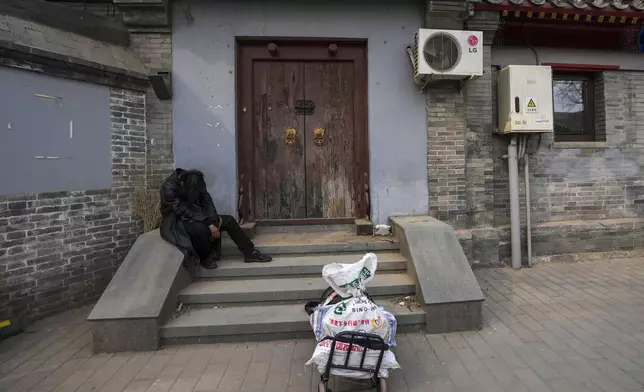 A man rests on the steps of a house in Beijing, China, Wednesday, April 3, 2024. (AP Photo/Tatan Syuflana)