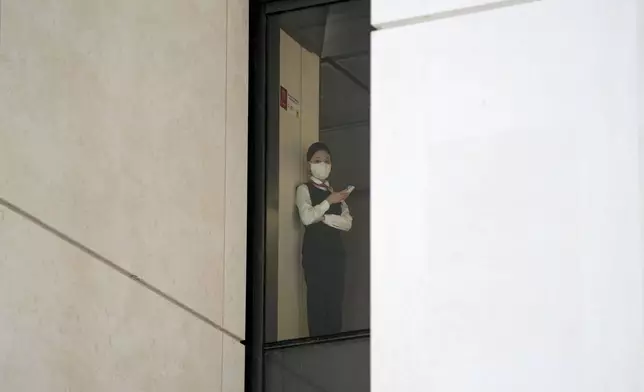 An employee stands near the window of an office building in Beijing, China, Monday, April 8, 2024. (AP Photo/Tatan Syuflana)