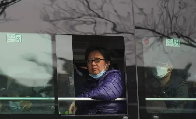 A woman looks out from a window of a city bus in Beijing, China, Wednesday, April 3, 2024. (AP Photo/Tatan Syuflana)
