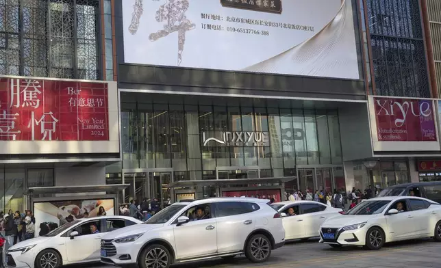 People look out from their car windows during rush hour traffic near a shopping mall in Beijing, China, Friday, April 5, 2024. (AP Photo/Tatan Syuflana)