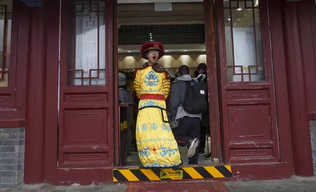 A man dressed in imperial costume depicting the emperor stands at a souvenir store near Great Wall of China on the outskirts of Beijing, Saturday, April 13, 2024. (AP Photo/Tatan Syuflana)