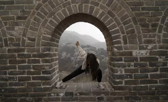 A woman poses for photos on the window of a watch tower along the Badaling section of the Great Wall of China on the outskirts of Beijing, Saturday, April 13, 2024. (AP Photo/Tatan Syuflana)