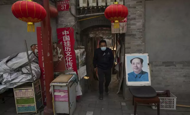 A man walks out from a Hutong near a portrait of late Chinese leader Mao Zedong in Beijing, China, Thursday, April 11, 2024. (AP Photo/Tatan Syuflana)