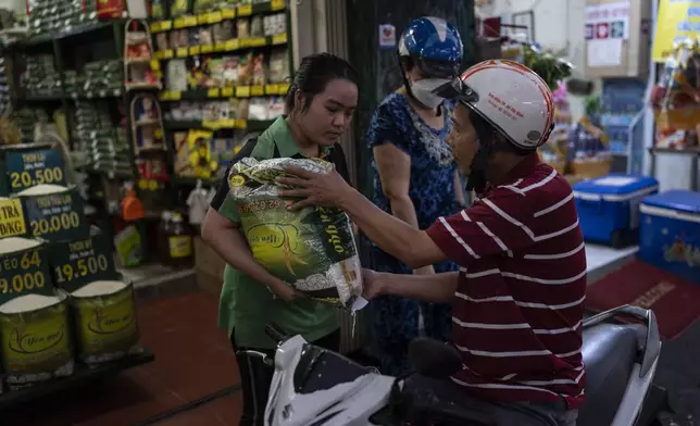 A rice shop employee hands a bag of rice to a customer sitting on a scooter in Ho Chi Minh City, Vietnam, on Wednesday, Jan. 24, 2024. Vietnam is the world's third largest rice exporter, and the staple importance to Vietnamese culture is palpable in the Mekong Delta. (AP Photo/Jae C. Hong)