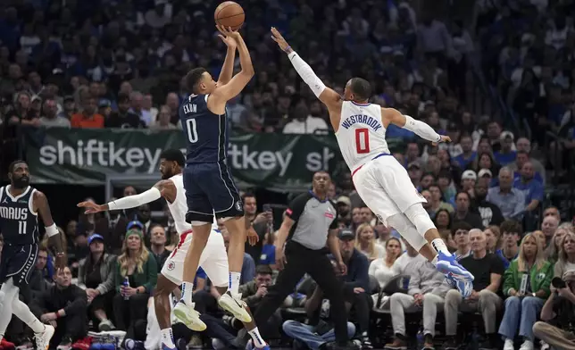 Dallas Mavericks guard Dante Exum, front left, shoots over Los Angeles Clippers guard Russell Westbrook, right, during the first half of Game 4 of an NBA basketball first-round playoff series Sunday, April 28, 2024, in Dallas. (AP Photo/Jeffrey McWhorter)