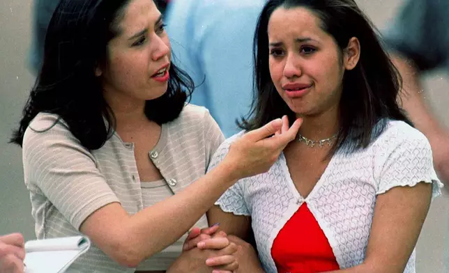 FILE - Kathy Zamora, left, comforts her friend Christine Medina, a sophomore at Columbine High School, after she escaped from the school when two gunmen entered the facility and went on a shooting rampage Tuesday, April 20, 1999, in the southwest Denver suburb of Littleton, Colo. (AP Photo/David Zalubowski, File)