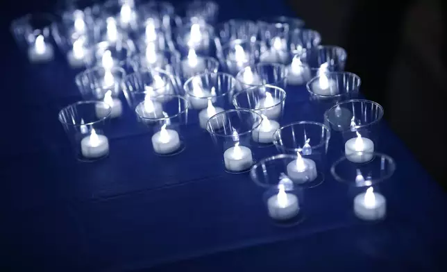 FILE - Tea lights sit illuminated during a vigil at the memorial for the victims of the massacre at Columbine High School nearly 20 years ago Friday, April 19, 2019, in Littleton, Colo. (AP Photo/David Zalubowski, File)