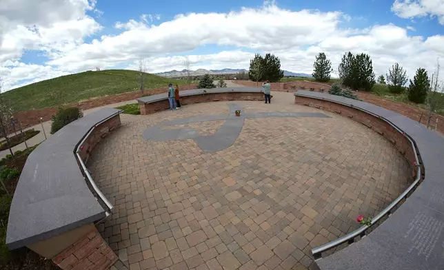 In this view through a fisheye lens, people visit the Columbine Memorial, Wednesday, April 17, 2024, in Littleton, Colo. Trauma still shadows the survivors of the horrific Columbine High School shooting as the attack's 25th anniversary approaches. (AP Photo/David Zalubowski)