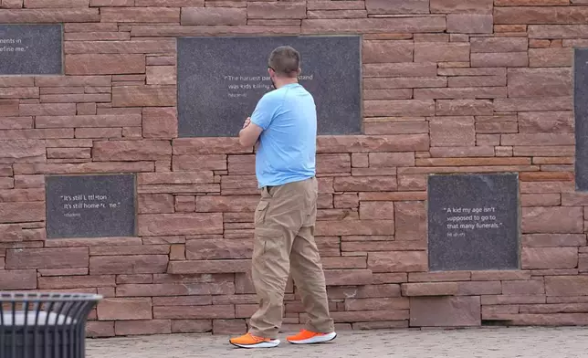 A visitor looks at the plaques on the wall of healing at the Columbine Memorial, Wednesday, April 17, 2024, in Littleton, Colo. Trauma still shadows the survivors of the horrific Columbine High School shooting as the attack's 25th anniversary approaches. (AP Photo/David Zalubowski)