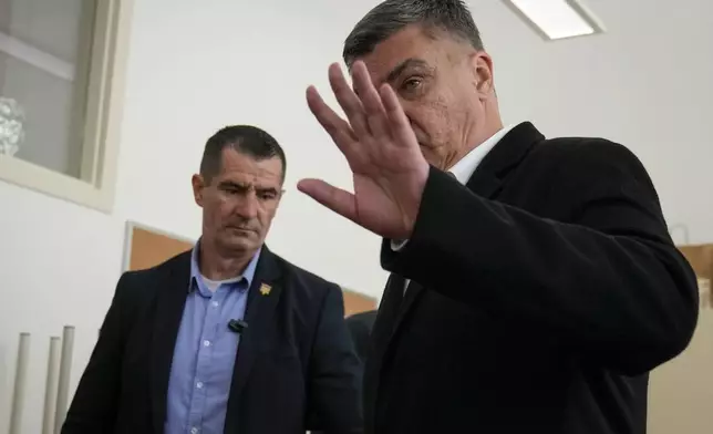 Croatia's President Zoran Milanovic, right, waves after casting his vote at a polling station in Zagreb, Croatia, Wednesday, April 17, 2024. Croatia is voting in a parliamentary election after a campaign that centered on a bitter rivalry between the president and prime minister of the small European Union and NATO member. (AP Photo/Darko Bandic)