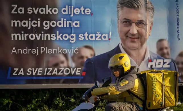 A delivery man waits for green light on a street in front of an election poster in Zagreb, Croatia, Sunday, April 14, 2024. Croatia this week holds an early parliamentary election following a campaign that was marked by heated exchanges between the country's two top officials, creating a political crisis in the Balkan country, a European Union and NATO member state. (AP Photo/Darko Bandic)