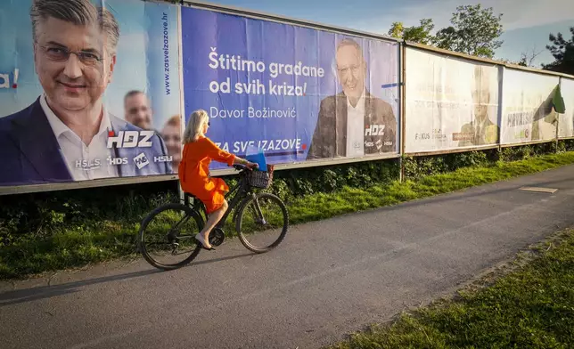 A cyclist rides past election posters in Zagreb, Croatia, Sunday, April 14, 2024. Croatia this week holds an early parliamentary election following a campaign that was marked by heated exchanges between the country's two top officials, creating a political crisis in the Balkan country, a European Union and NATO member state. (AP Photo/Darko Bandic)