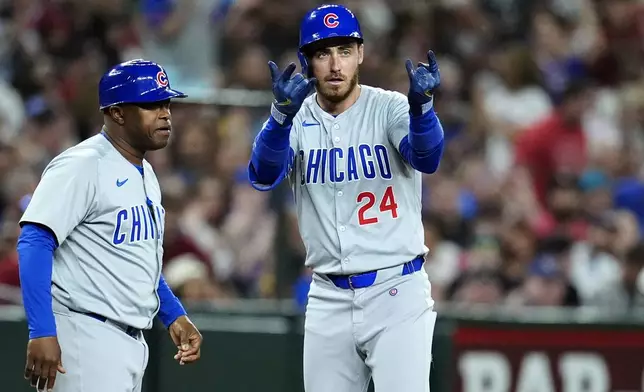 Chicago Cubs' Cody Bellinger, right, celebrates his run-scoring triple against the Arizona Diamondbacks as Cubs third base coach Willie Harris looks on during the fifth inning of a baseball game Tuesday, April 16, 2024, in Phoenix. (AP Photo/Ross D. Franklin)