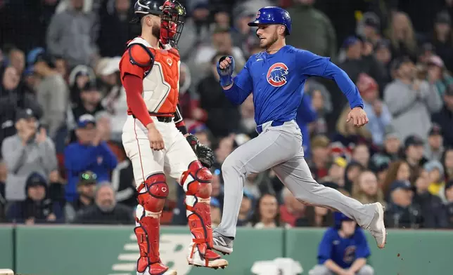 Chicago Cubs' Michael Busch, right, scores in front of Boston Red Sox catcher Connor Wong, left, on a two-run double by Patrick Wisdom during the seventh inning of a baseball game, Friday, April 26, 2024, in Boston. (AP Photo/Michael Dwyer)