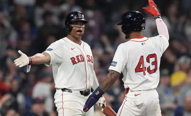 Boston Red Sox's Ceddanne Rafaela (43) celebrates with teammate Rafael Devers after scoring on a two-run triple by Jarren Duran during the sixth inning of a baseball game, Sunday, April 28, 2024, in Boston. (AP Photo/Michael Dwyer)