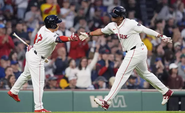 Boston Red Sox's Rafael Devers celebrates with Masataka Yoshida after scoring on an RBI single by Connor Wong during the first inning of a baseball game against the Chicago Cubs, Sunday, April 28, 2024, in Boston. (AP Photo/Michael Dwyer)